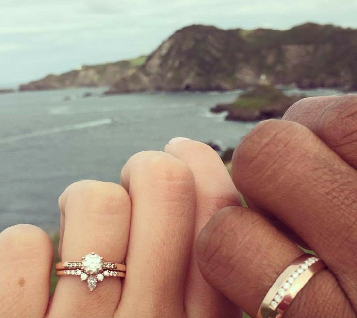 two people holding each other's hands with the ocean in the background