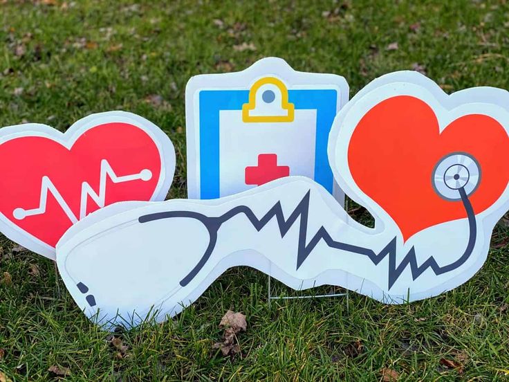 three heart shaped cut outs sitting on top of the grass with a stethoscope