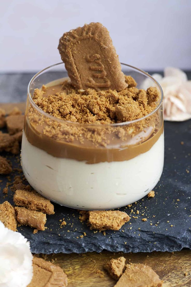 a dessert in a small glass bowl with graham crackers on the side and a spoon sticking out of it