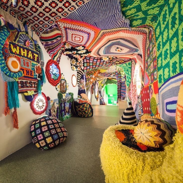 an art gallery with many colorful knitted objects hanging from it's walls and ceiling