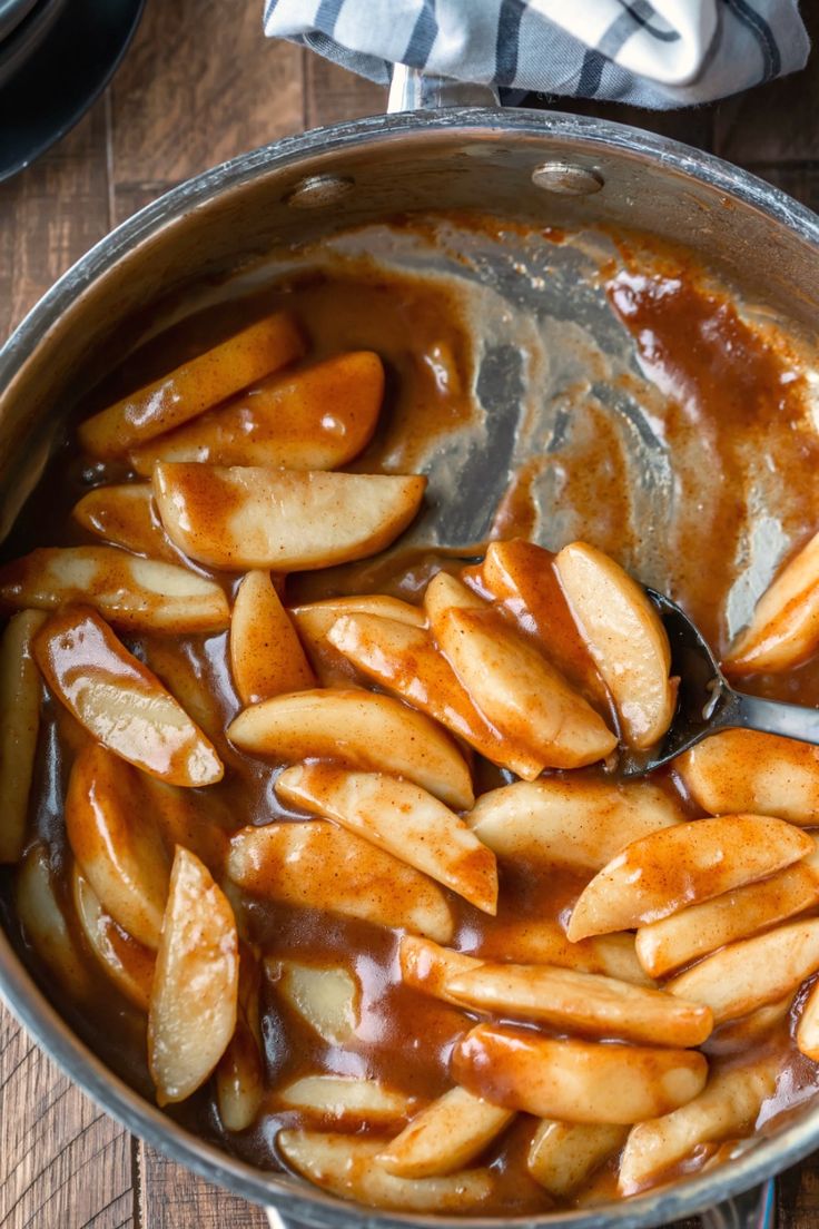 apples are being cooked in a pot with caramel sauce