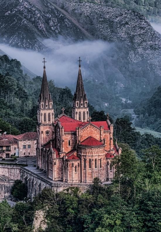 an old church surrounded by trees and mountains