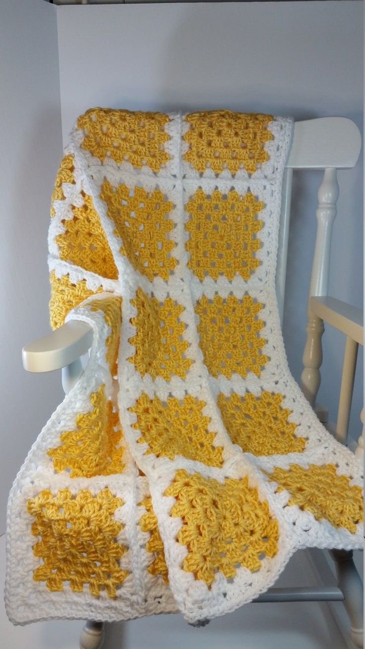 a crocheted blanket sitting on top of a chair next to a white rocking chair