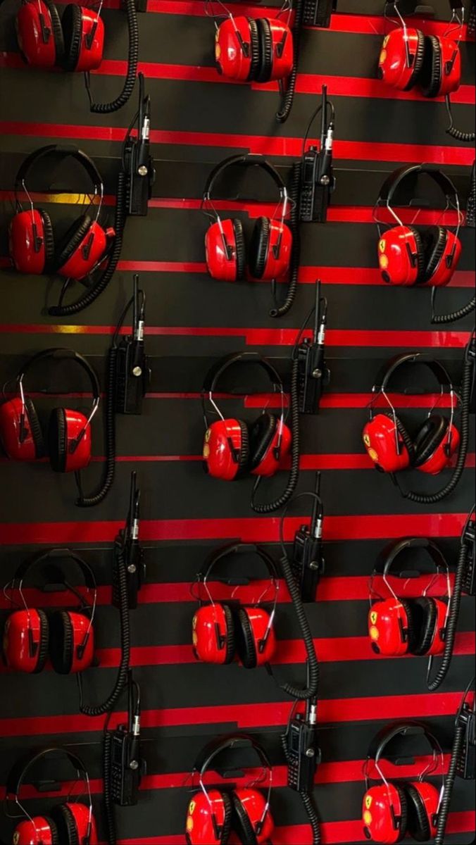 red headphones are lined up against a black and red striped wall with ear muffs