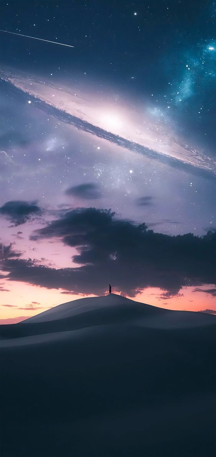 a person standing on top of a hill under a sky filled with stars and clouds