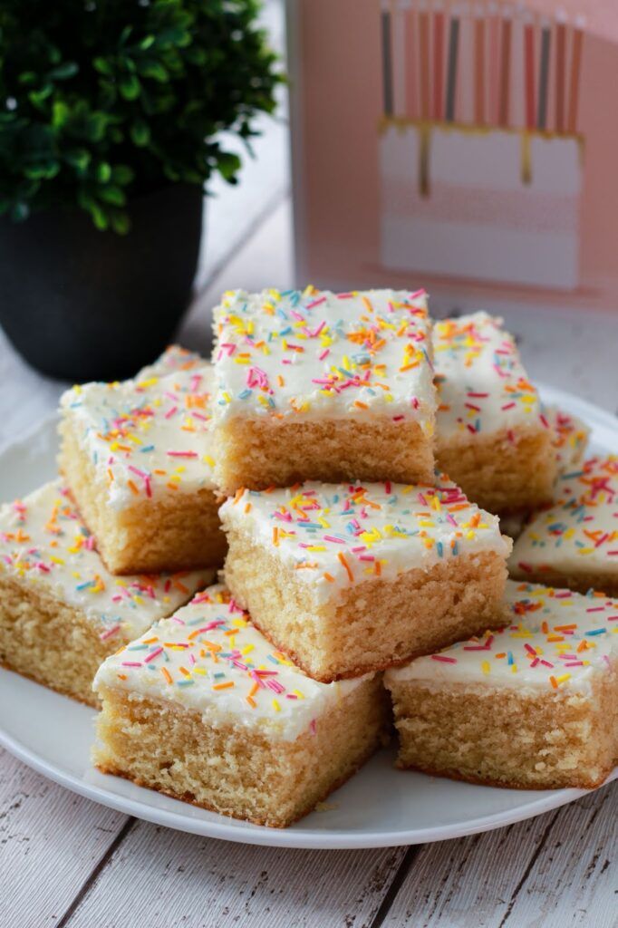 a white plate topped with lots of frosting and sprinkles next to a potted plant