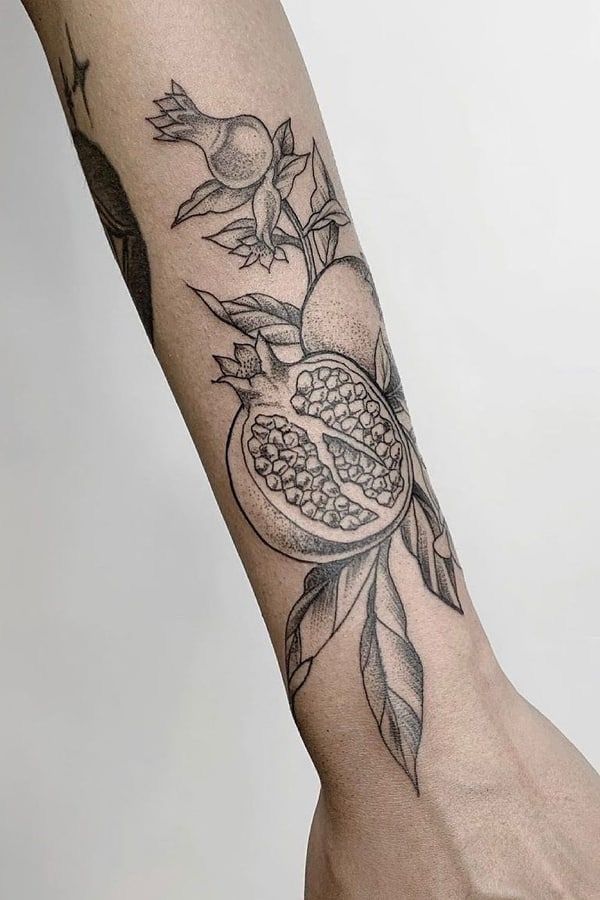 a person's arm with a pomegranate and leaves tattoo on it