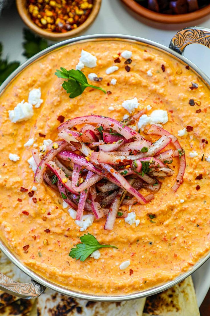 a bowl filled with hummus, onions and feta cheese