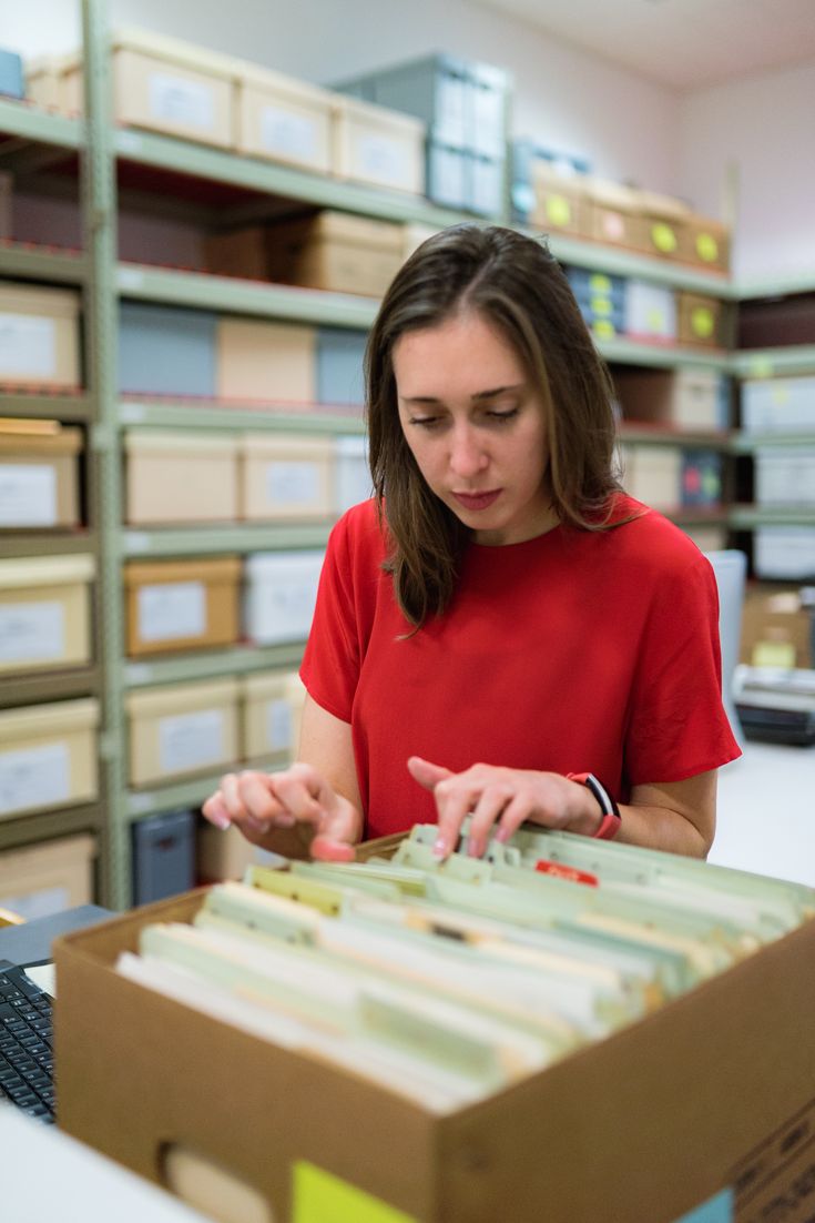 a woman in a red shirt is looking at files