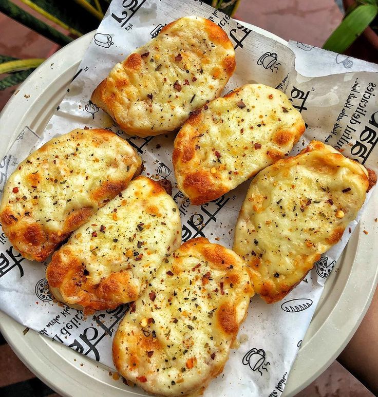 four pieces of bread sitting on top of a white paper plate covered in cheese and seasoning