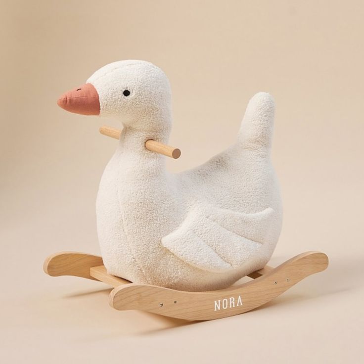 a white duck sitting on top of a wooden rocking toy