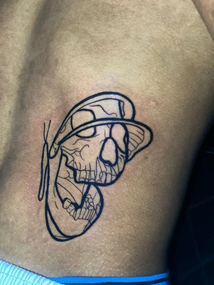 a man with a skull tattoo on his stomach wearing a hat and holding a baseball bat