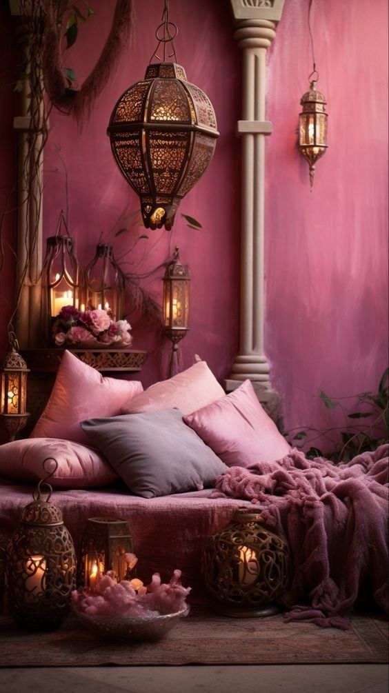 a bed covered in lots of pillows next to a lamp and some lights on the wall