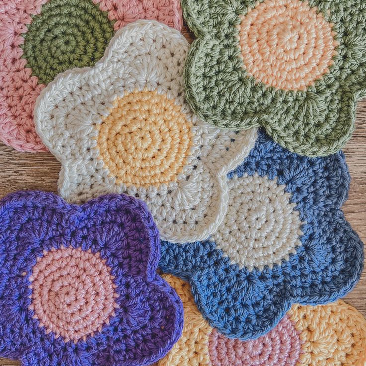 several crocheted flower coasters on a wooden surface