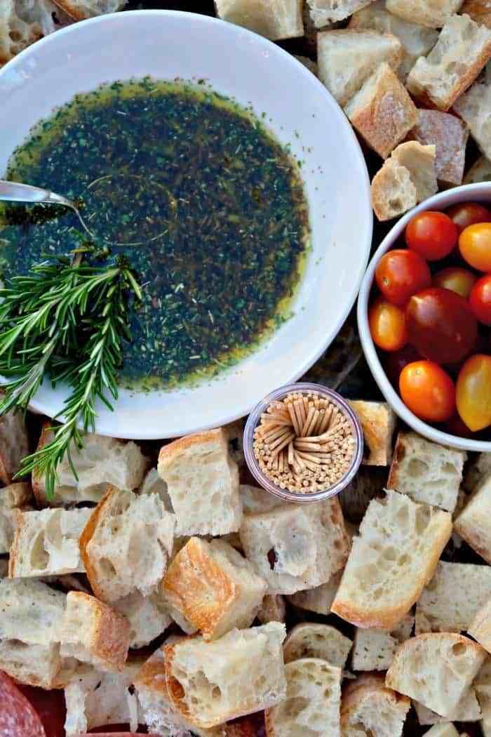 bread, tomatoes, and other food items are on a table with olive oil in a bowl