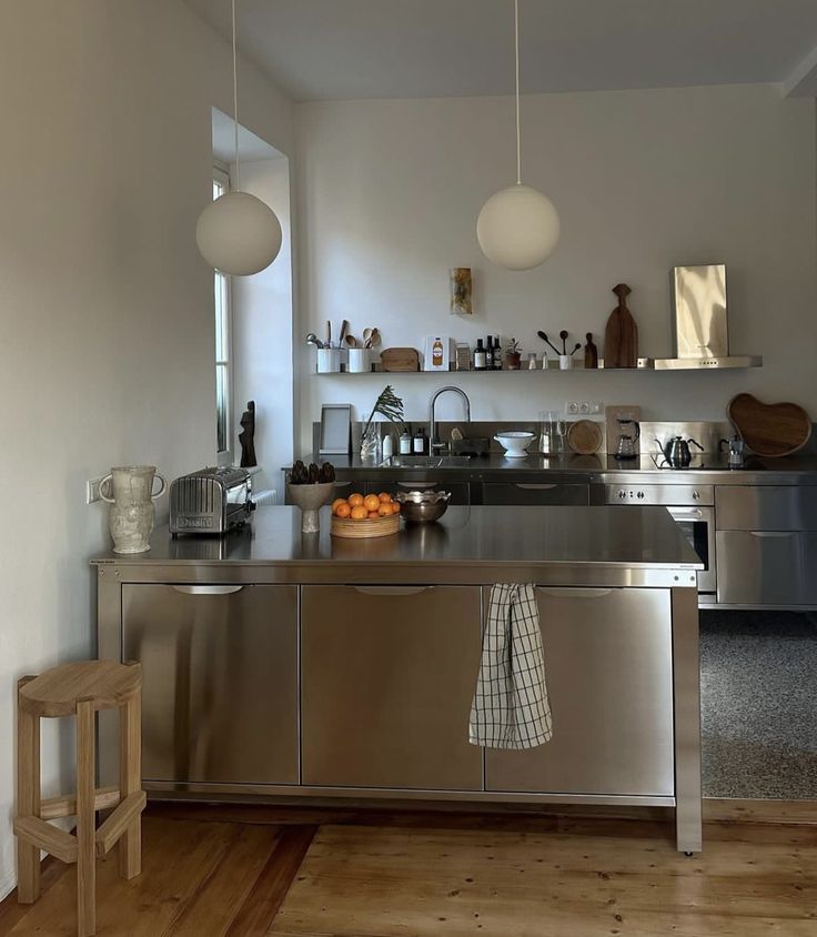 a kitchen with stainless steel counter tops and wooden flooring, along with hanging lights