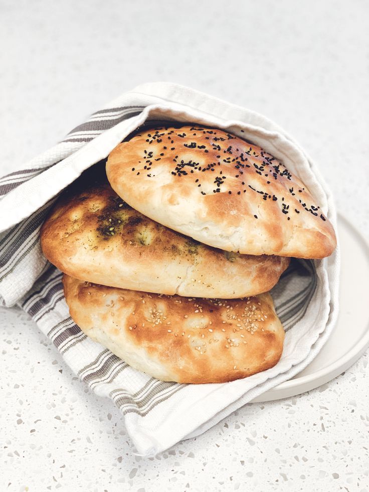 three bagels sitting on top of a white plate covered in sesame seed sprinkles