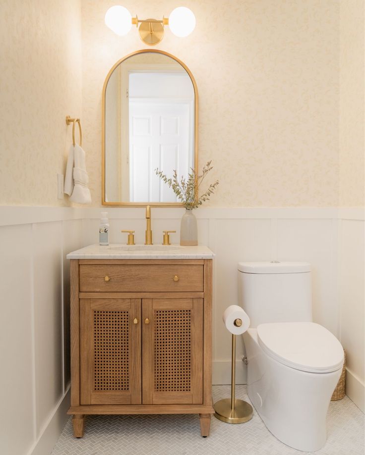 a white toilet sitting next to a wooden cabinet in a bathroom under a large mirror