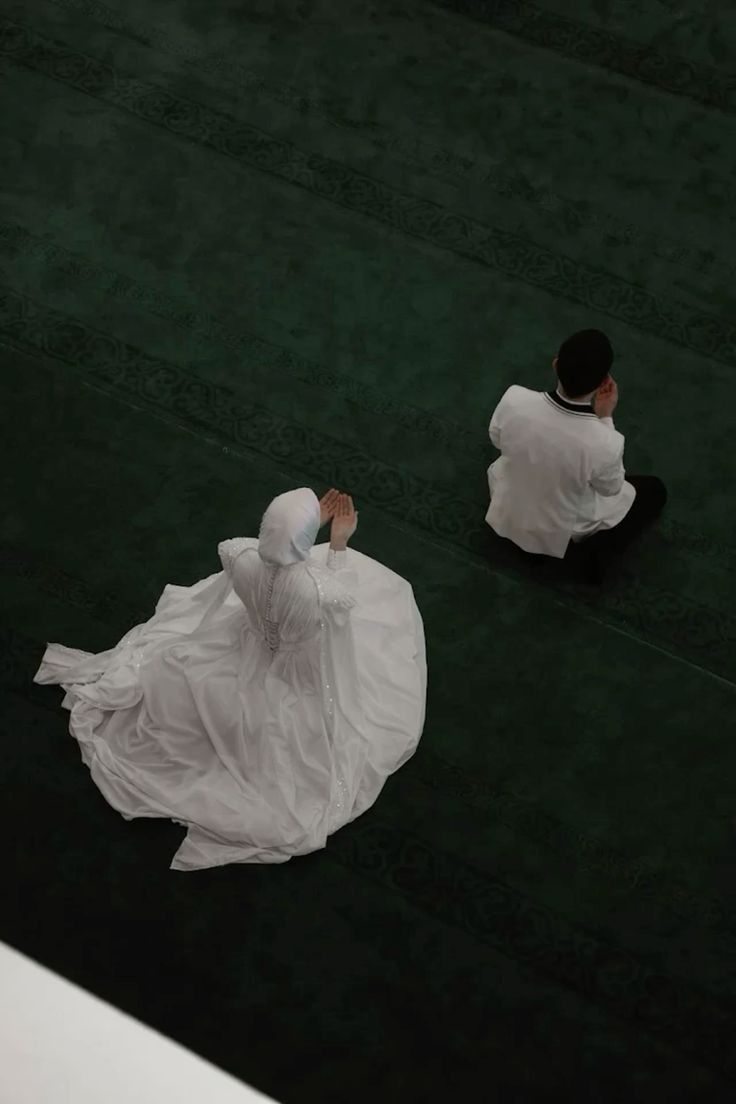 two people dressed in white sitting on the ground