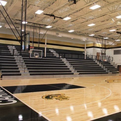 an empty basketball court in a gym with lights on the ceiling and bleachers