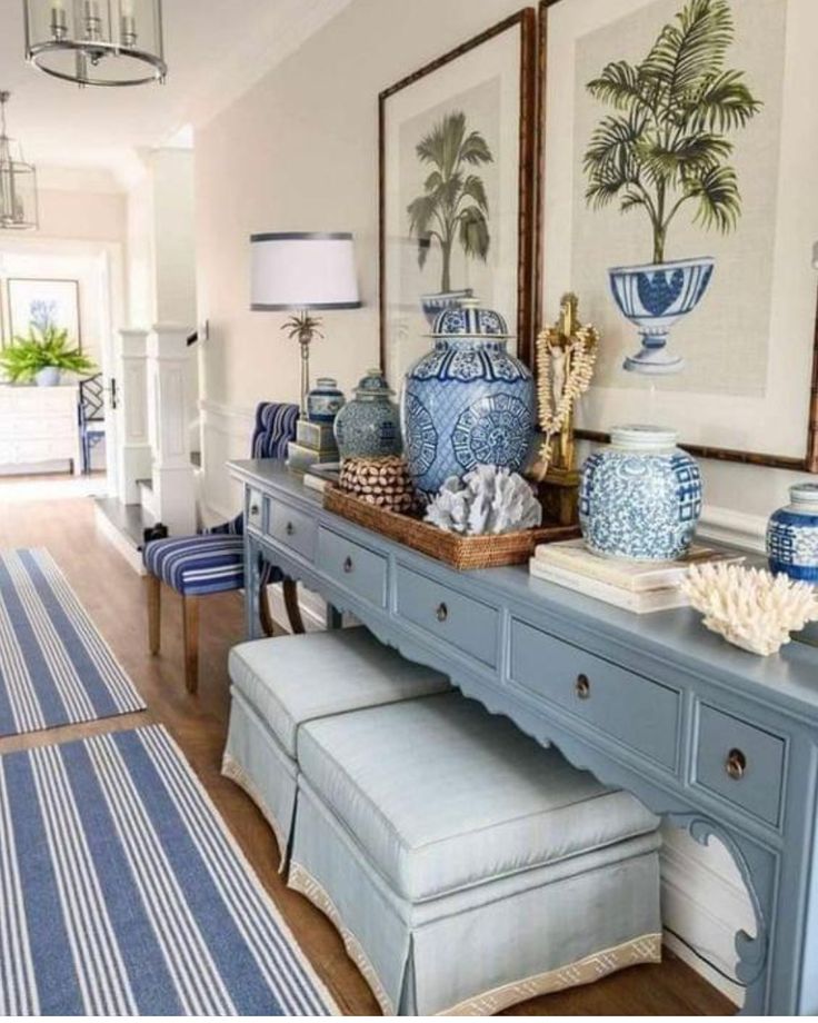 a blue and white entryway with vases on the sideboard, two chairs and a bench in front of it