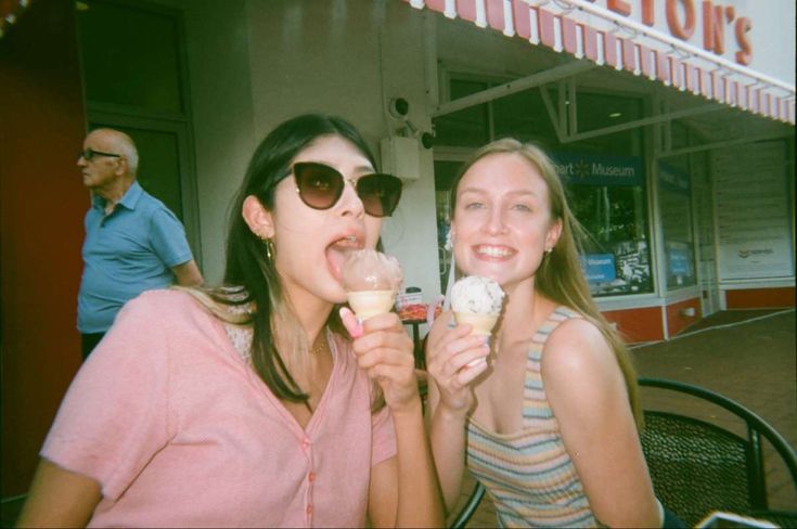 two women are eating ice cream outside