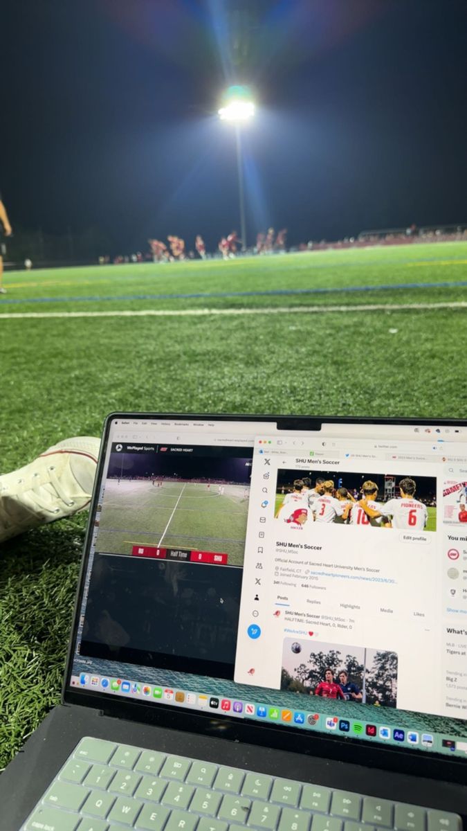 a laptop computer sitting on top of a grass covered field next to a soccer field