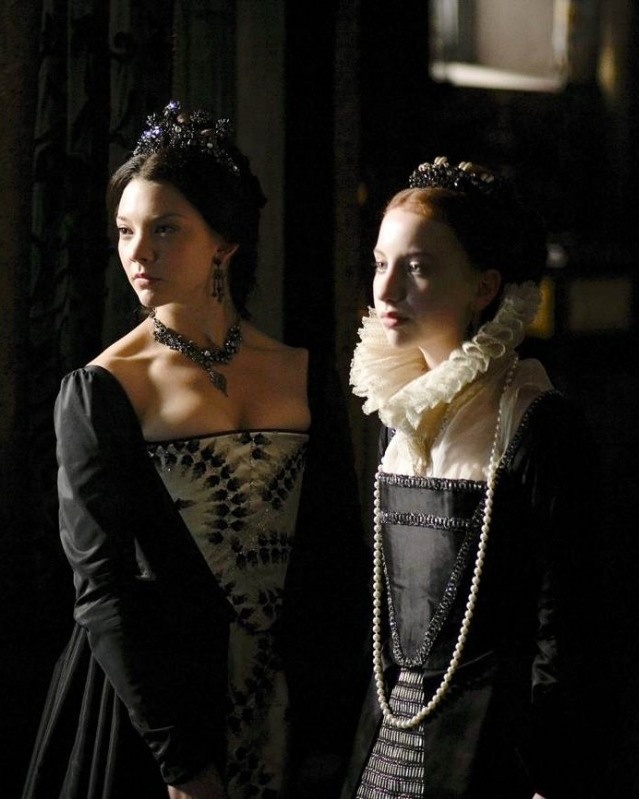 two women dressed in period clothing standing next to each other, one wearing a tiara