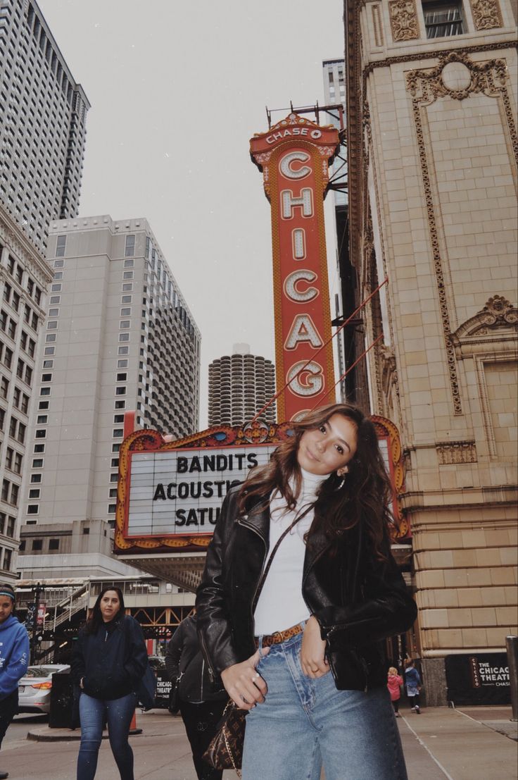 a woman standing in front of the chicago theatre sign with her hands on her hips