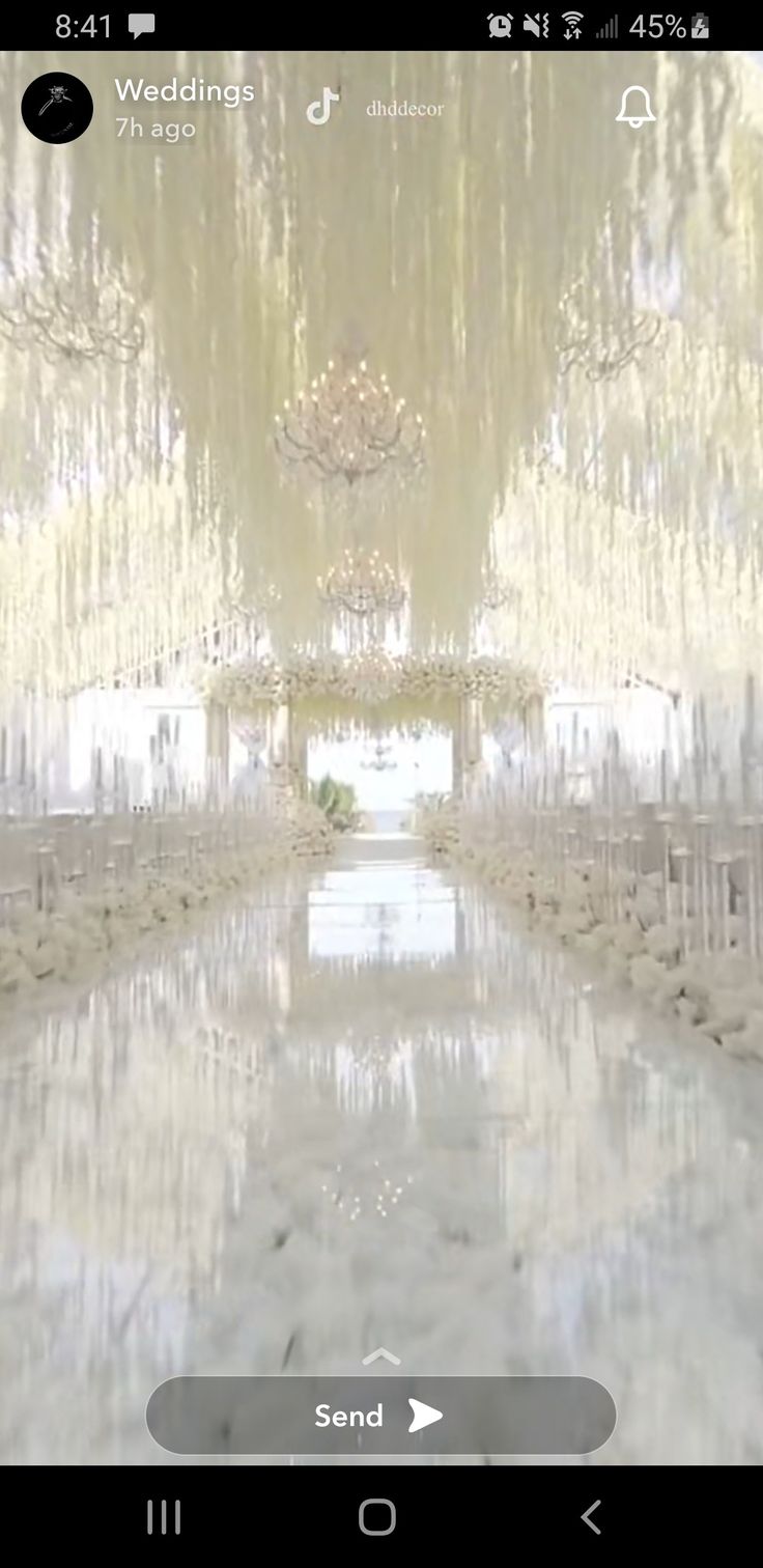 the aisle is decorated with white flowers and chandelier hanging from the ceiling above