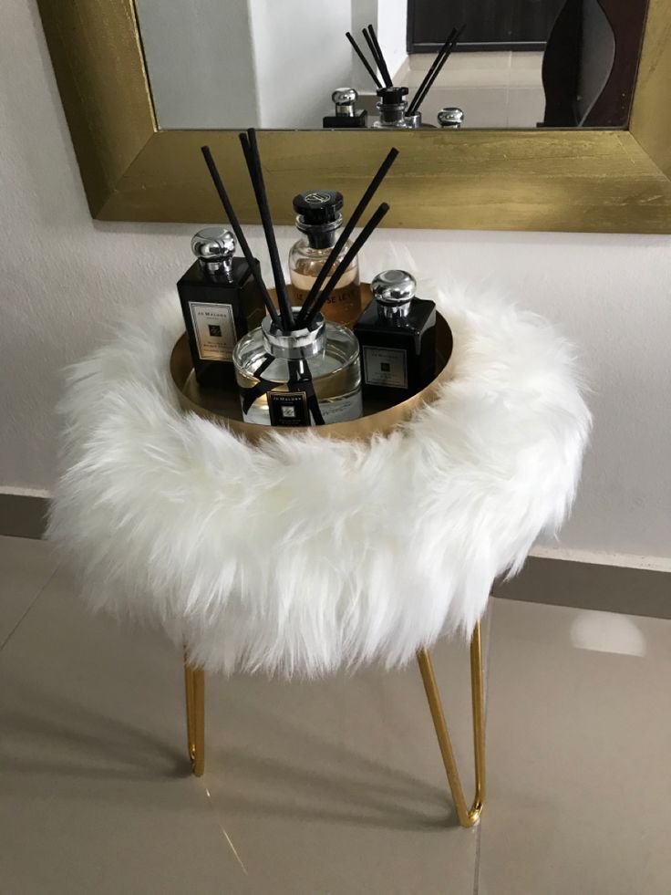 a white fur stool with candles and bottles on it