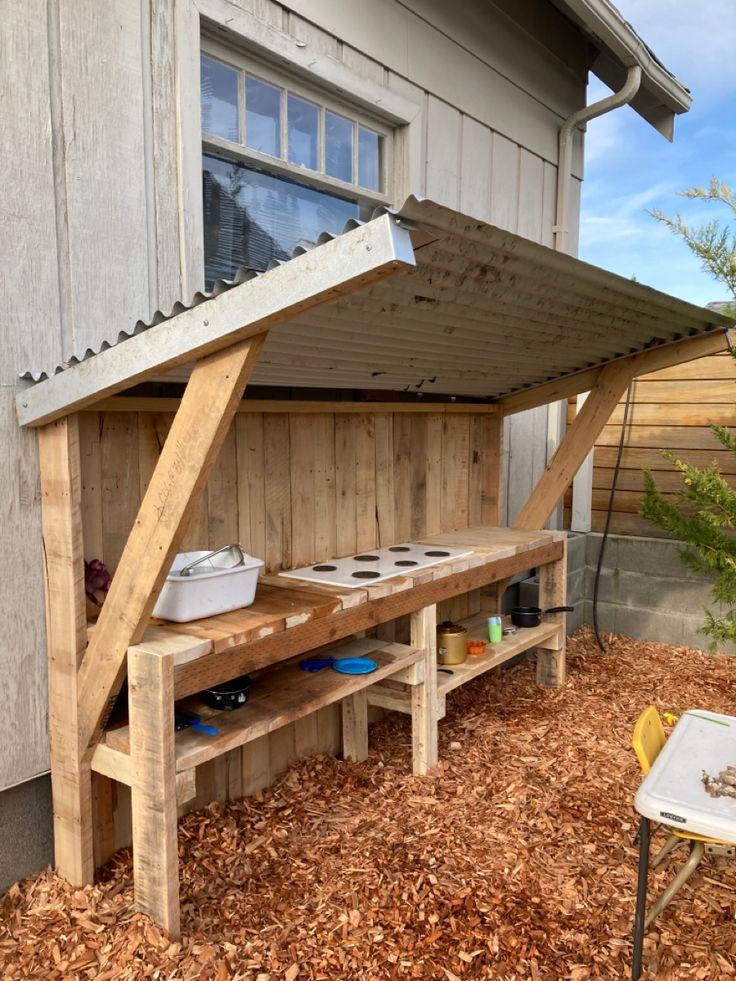 a wooden bench sitting in the middle of a yard next to a building with an awning over it