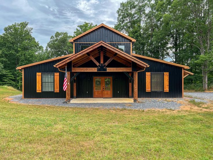 a large black barn with an american flag on the front door and two doors open