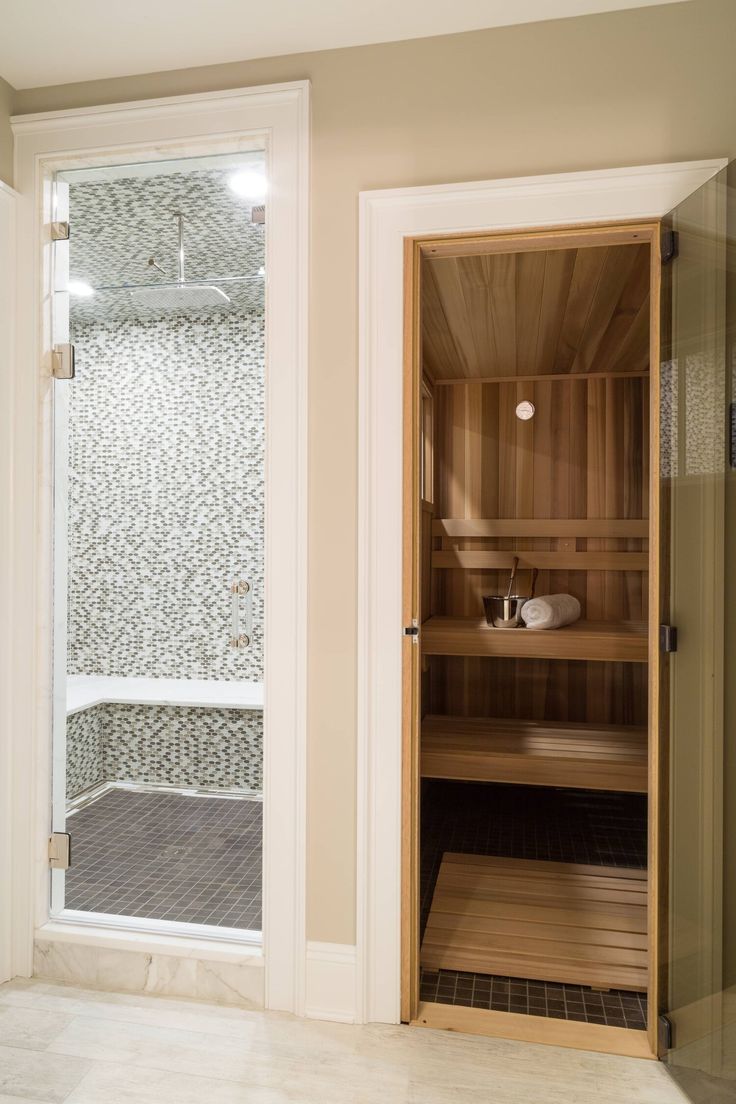 an empty sauna in the corner of a room with glass doors and white walls