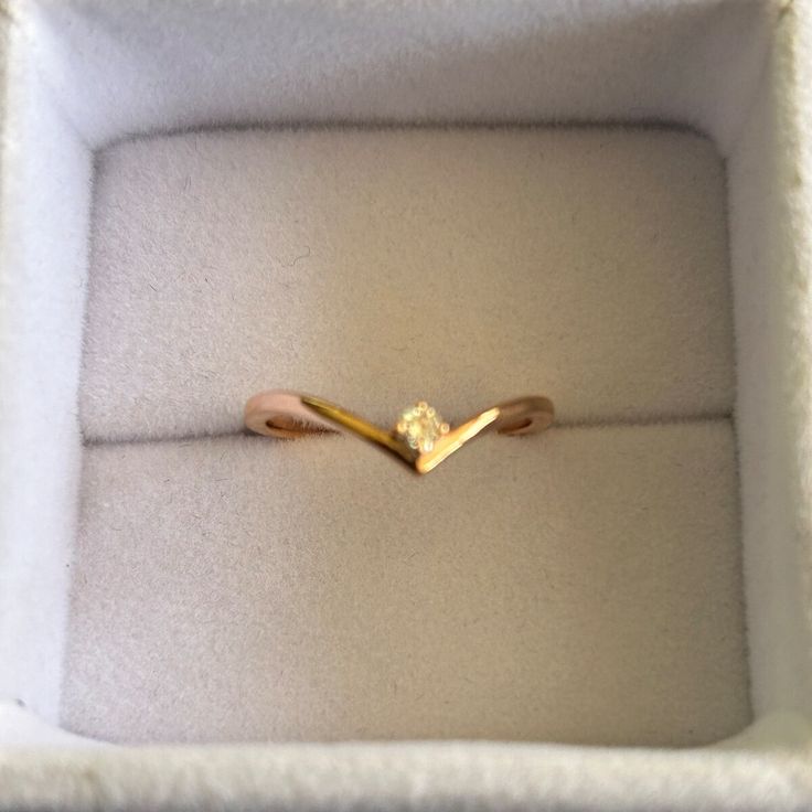 a gold ring in a white box with a diamond on it's middle finger