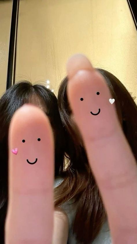 two fingers with smiley faces drawn on them are shown in front of a woman's face