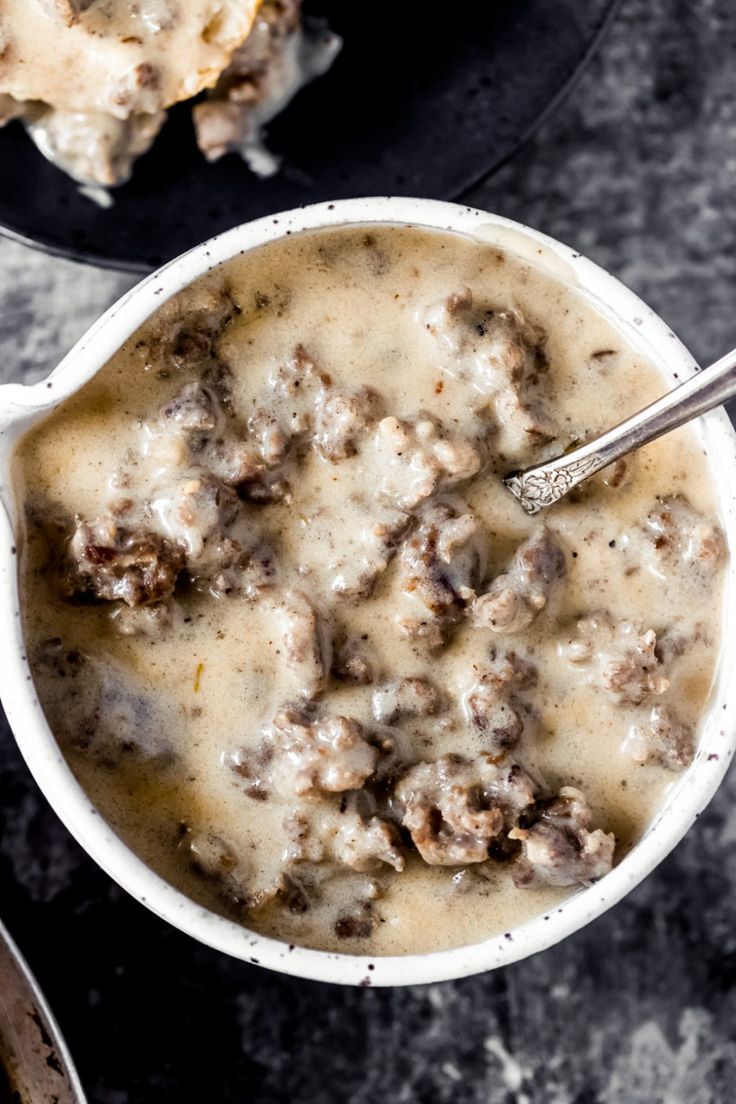 a bowl filled with meat and gravy on top of a table