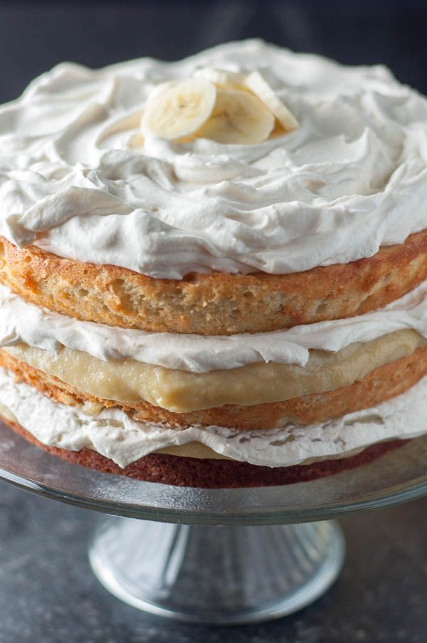 a layered cake with bananas on top is sitting on a glass platter, ready to be eaten