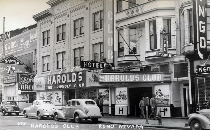 an old black and white photo of cars parked on the side of a street in front of buildings