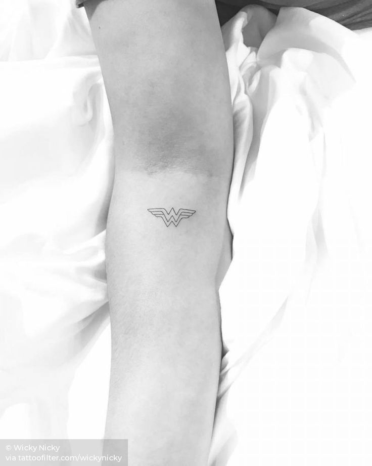 a woman's arm with a small wonder logo tattoo on the left inner arm