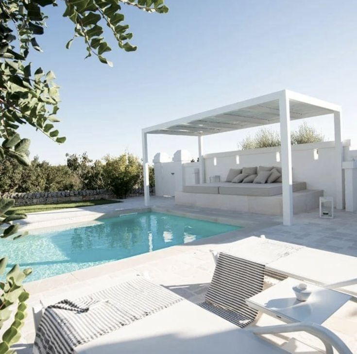 an outdoor pool area with lounge chairs and a covered seating area next to the swimming pool