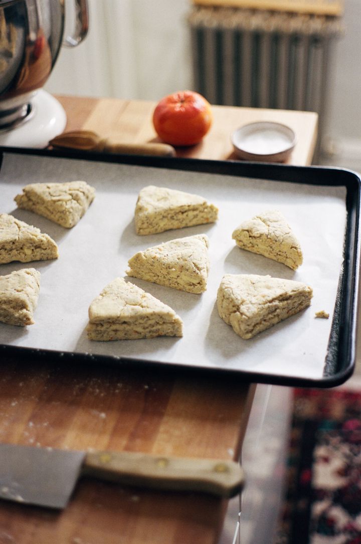 six scones on a baking sheet ready to go into the oven with an apple in the background