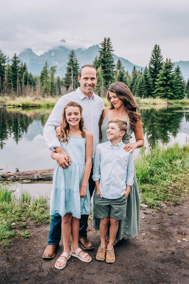 a man and two children standing in front of a lake