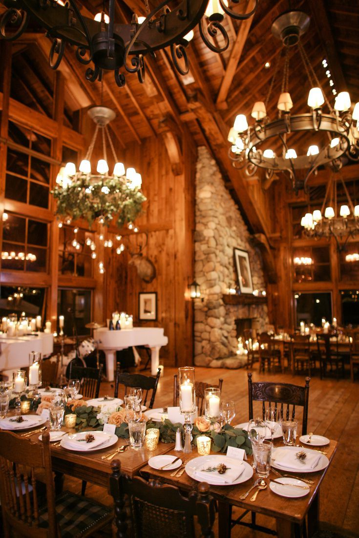 a dining room filled with lots of tables covered in white plates and place settings, surrounded by chandeliers