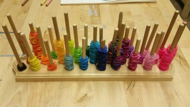 there are many different colored spools on the wooden table with paintbrushes