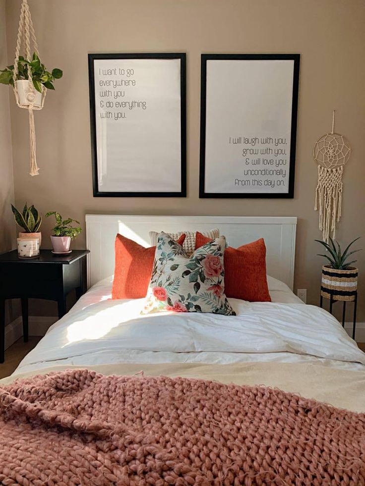 a bed with two pictures above it and some plants on the nightstands in front of it