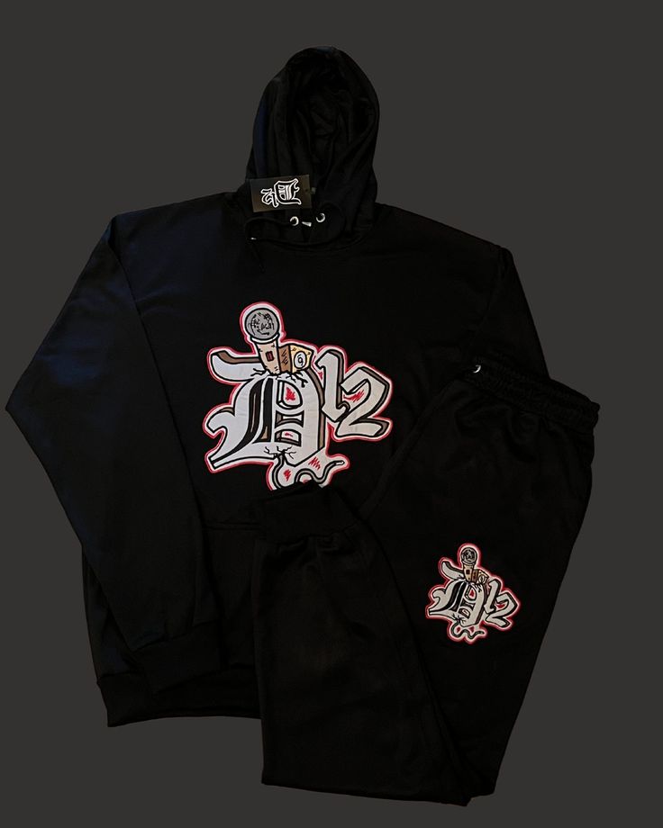 Embrace the thrill of risk-taking in the streets with the D12 Mic Check Embroidered Jogging Suit. The bold embroidered logo adds a touch of edginess to your style, while the comfortable fit allows you to conquer any adventure. Elevate your look and feel motivated to take on the challenge with this statement piece! Long Sleeve Letter Print Streetwear Sets, Letter Print Long Sleeve Sets For Streetwear, Long-sleeve Letter Print Streetwear Sets, Hooded Graphic Print Tracksuit For Streetwear, Winter Tracksuit With Graphic Print For Streetwear, Winter Sports Tracksuit With Graphic Print, Winter Graphic Print Tracksuit For Streetwear, Cotton Tracksuit With Graphic Print For Sports, Cotton Graphic Print Tracksuit For Sports