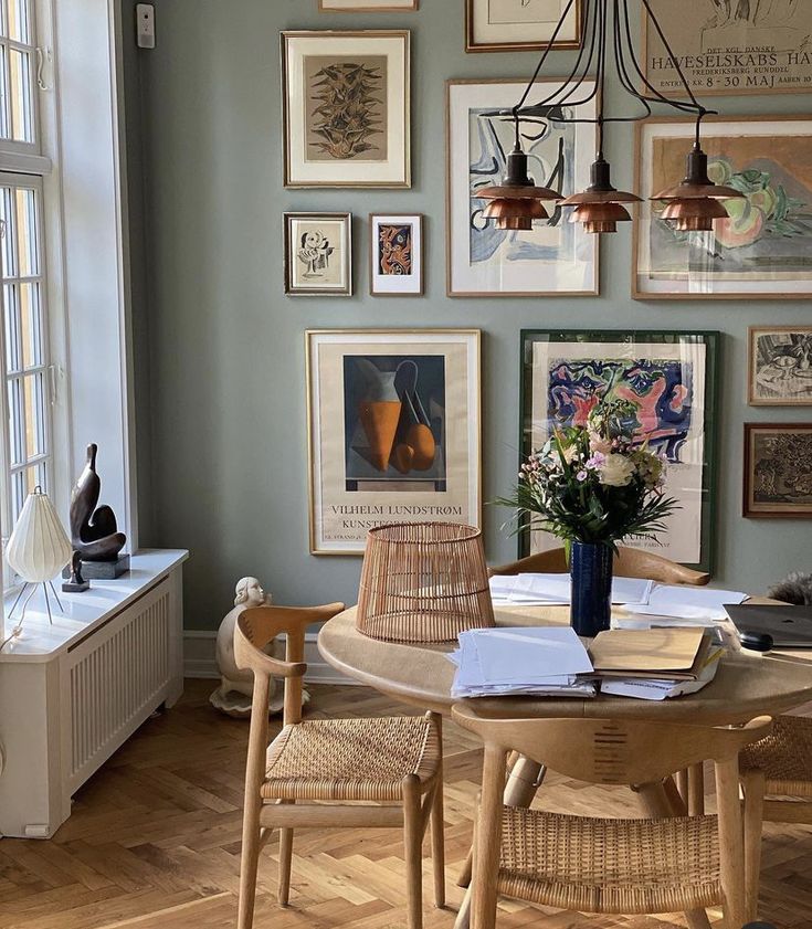 a dining room table with chairs and pictures on the wall above it, along with other decor items