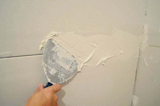 a person is using a paint roller to paint a wall with white paint on it