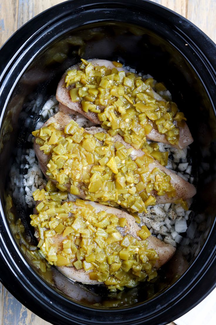 two pieces of cooked meat in a crock pot with rice and vegetables on the side